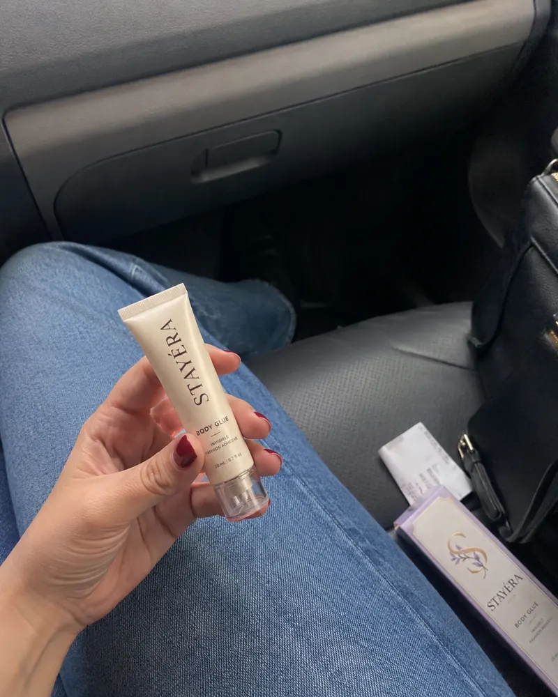 שפופרת STAYÉRA BODY GLUE ביד בתוך רכב, האריזה מונחת על המושב